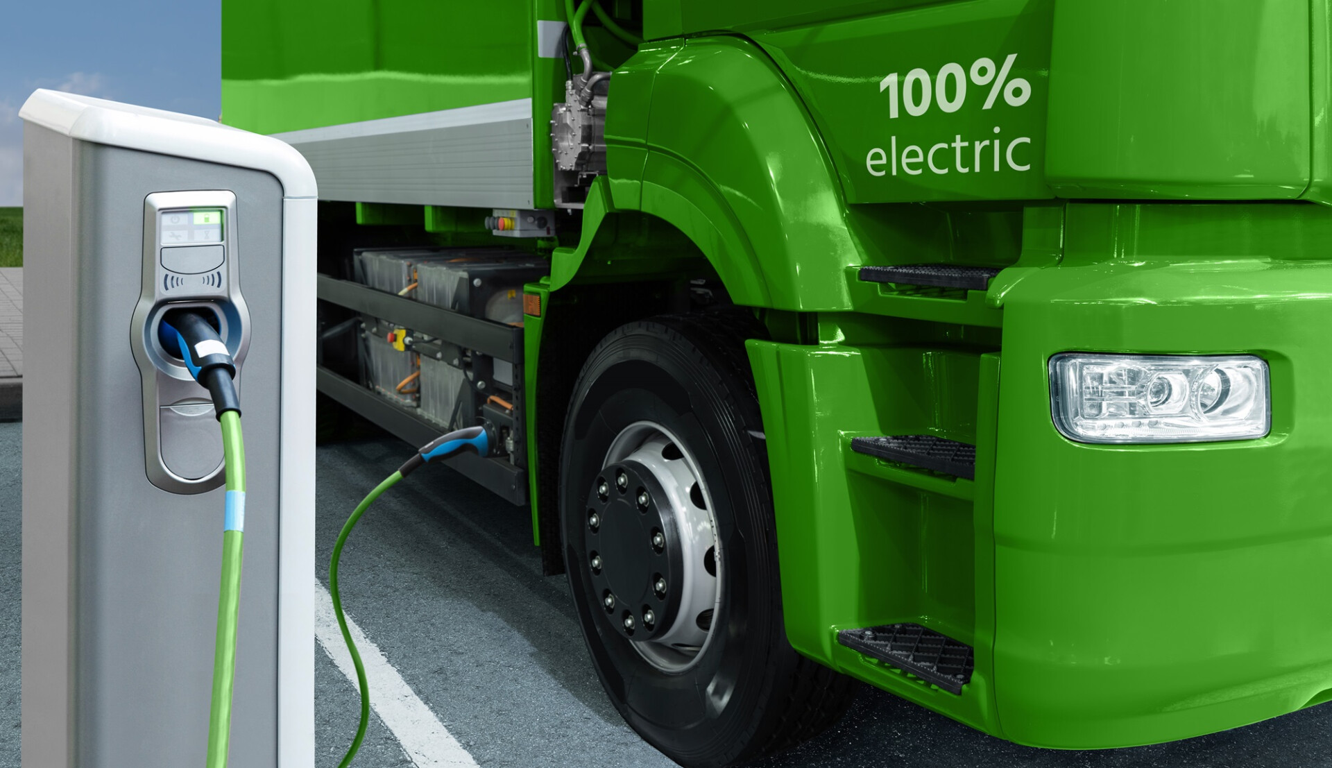 Green electric truck is charged from the charging station a green truck with an electric charger plugged into it